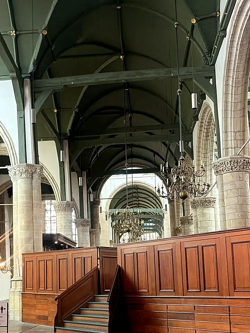 Zicht door het schip van de Sint-Janskerk richting het koor, met houten gewelven en kroonluchters